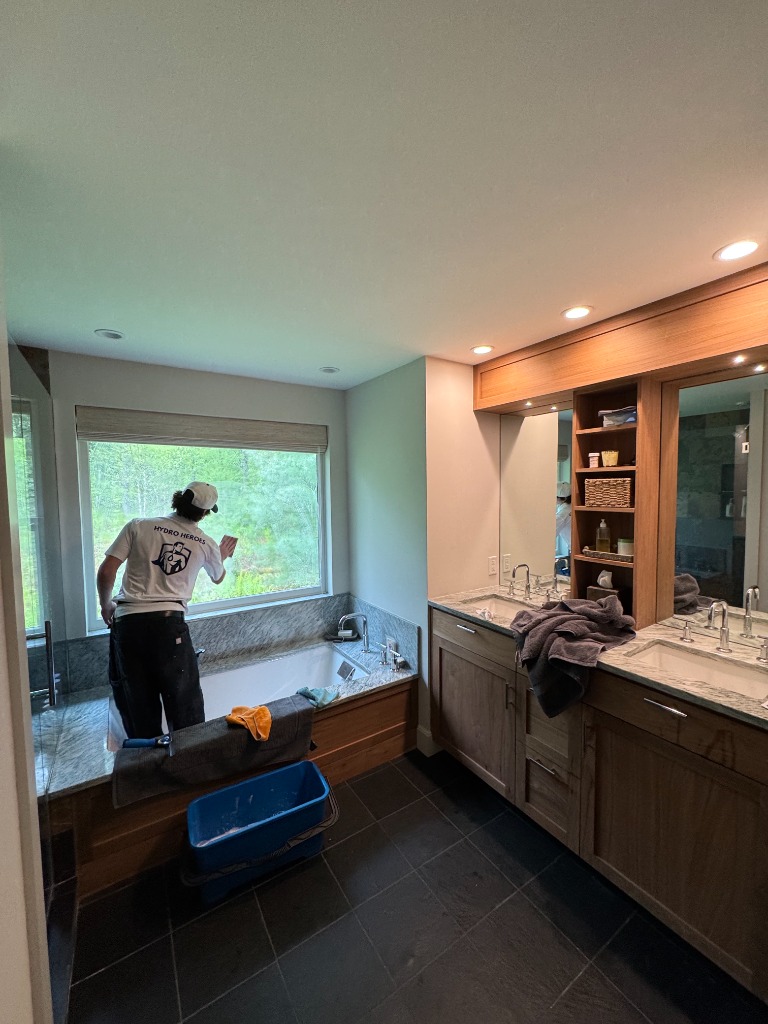 Hydro Heroes team member cleaning windows inside a bathroom